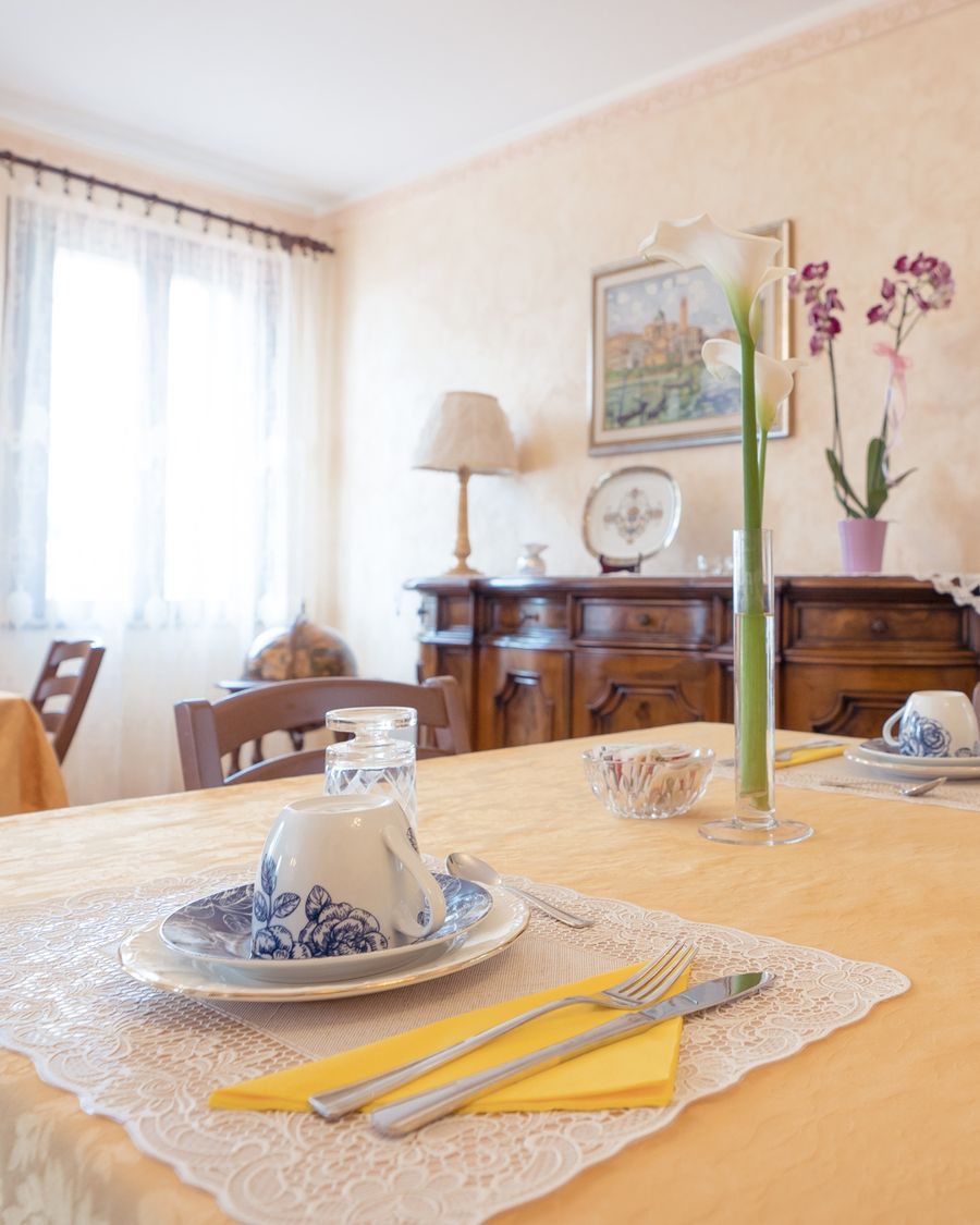 La tavola della colazione apparecchiata con porcellane bianche e blu e una calla